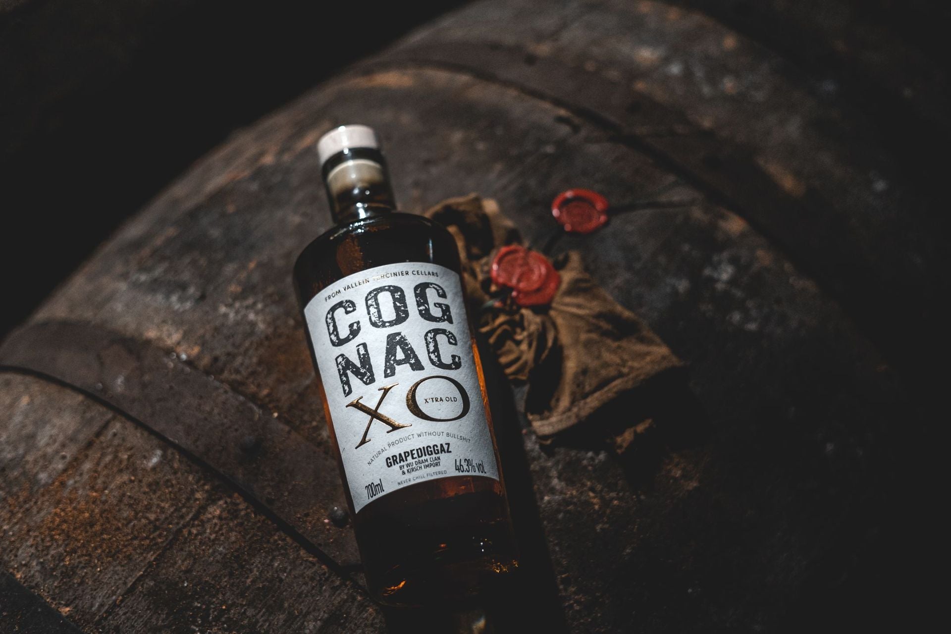 Flasche Cognac XO auf einem Holzfass, daneben Wachssiegel und Handschuh. 700ml, dunkle Atmosphäre, edle Reifung, Tasting-Titelbild.